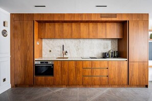Eine moderne Küche mit Holzschränken, einem eingebauten Backofen und einer Marmorarbeitsplatte.