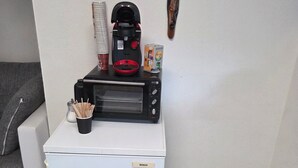 Une petite cuisine équipée comprenant un réfrigérateur Bosch, une machine à café, un grille-pain et une petite poubelle.