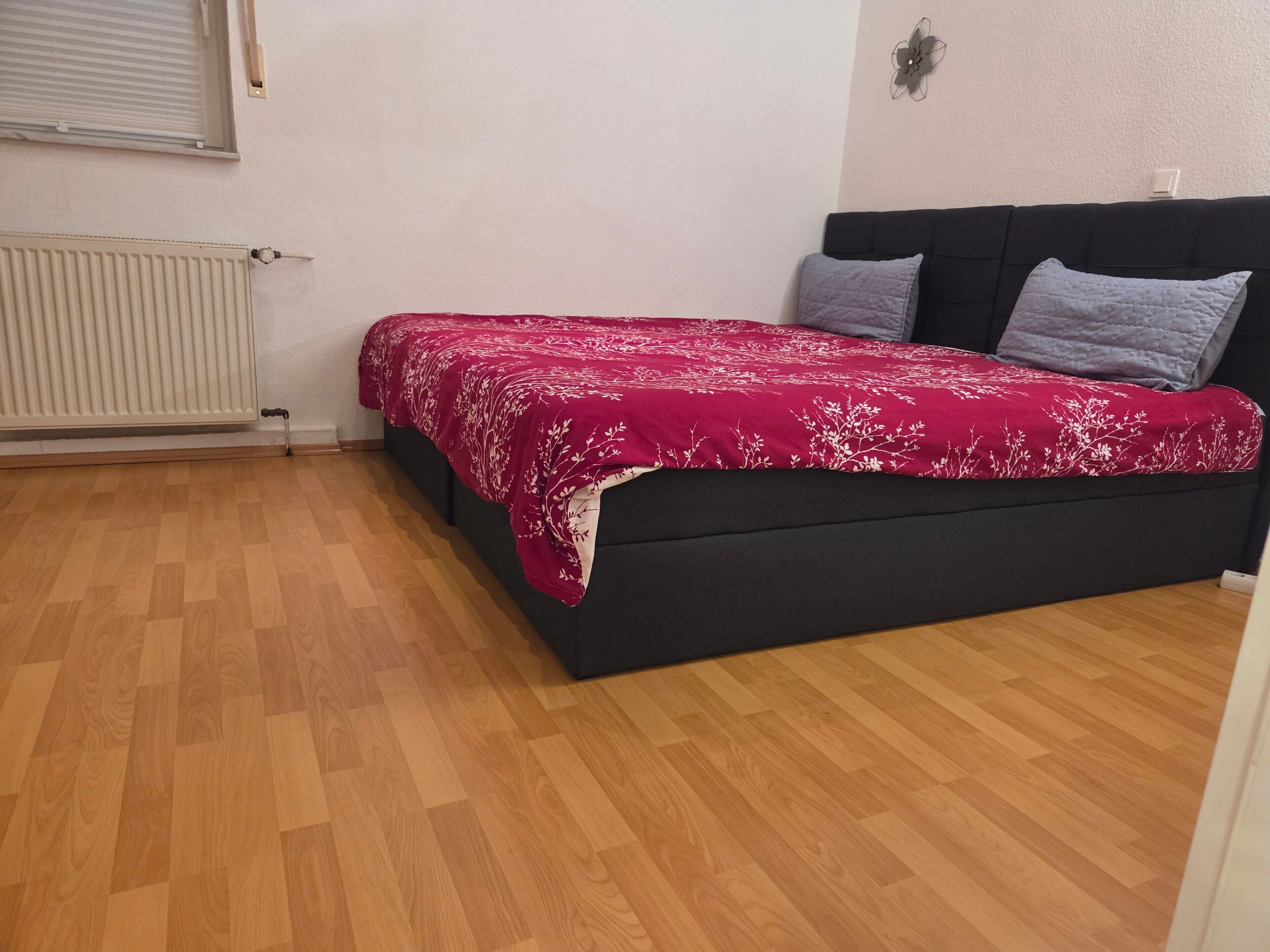 Een kamer met een bed, een radiator en een raam.