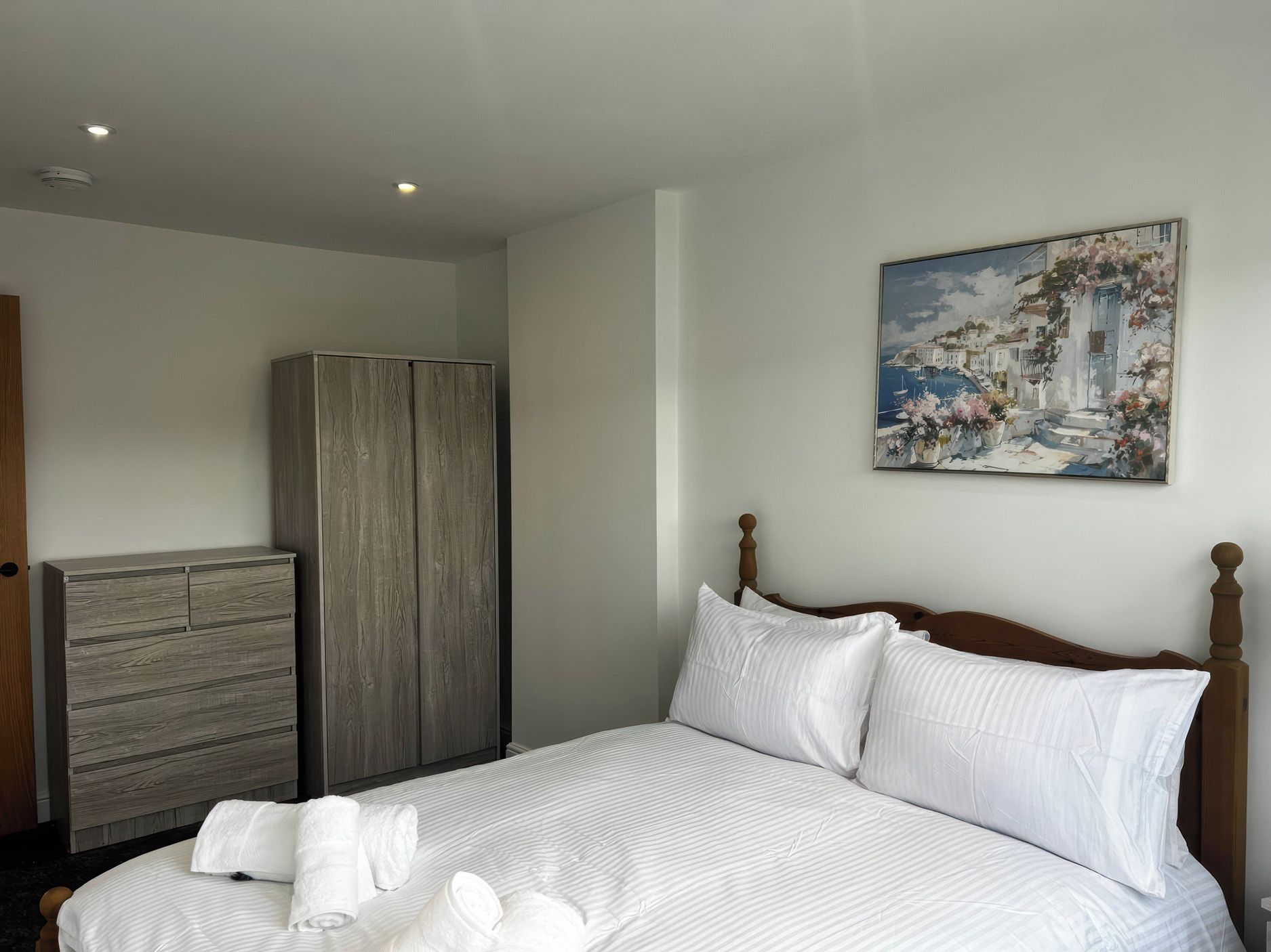Habitación de hotel con cama, armario y un cuadro en la pared.