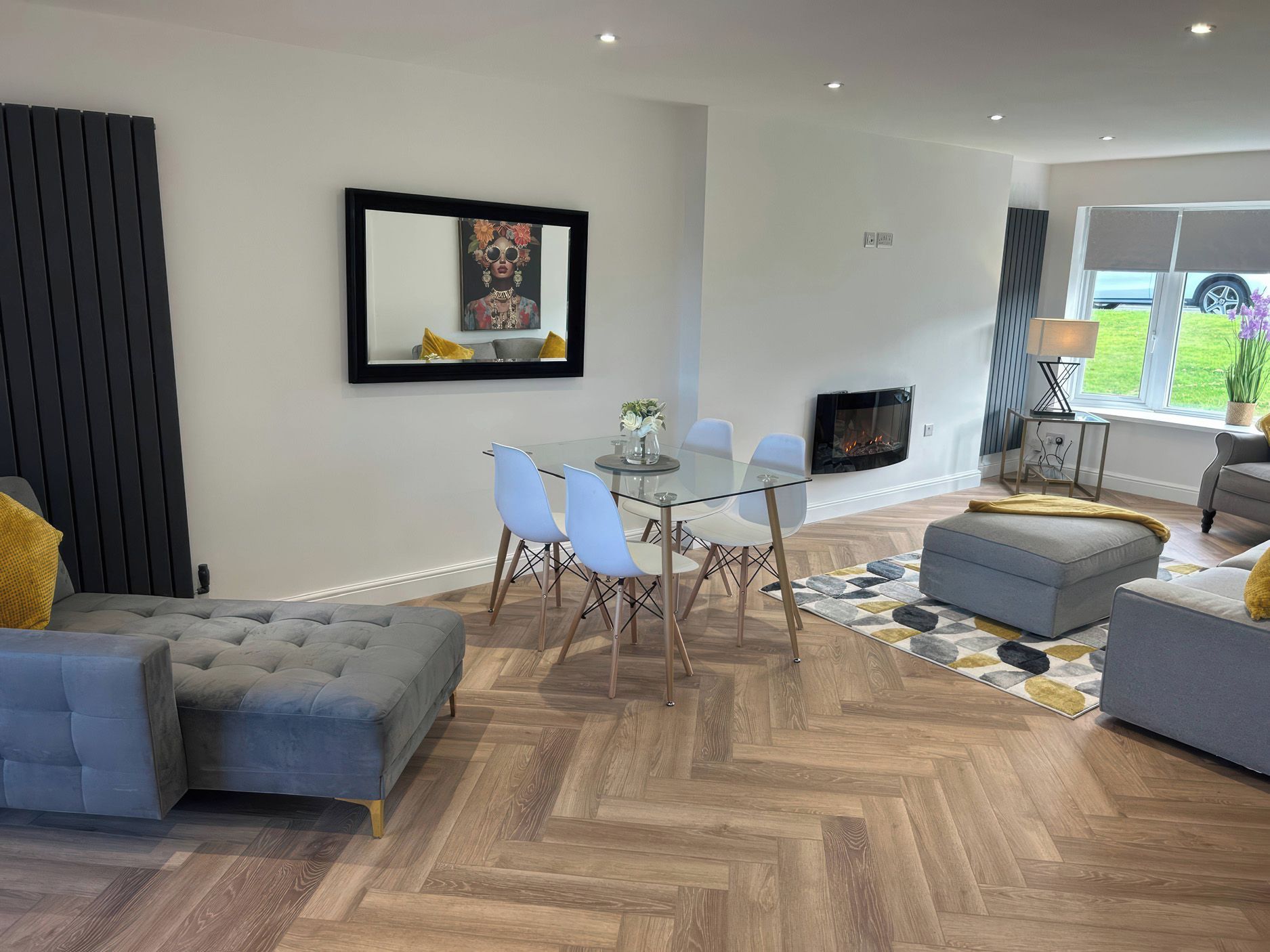 A modern living room with a fireplace, a dining area with a glass table, and a sofa.