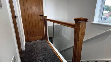 A wooden door with a glass panel, a carpeted staircase, and a window with a view of the outside.