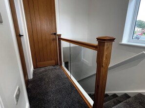 A wooden door with a glass panel, a carpeted staircase, and a window with a view of the outside. - 21 Bastion Gardens (Prestatyn)