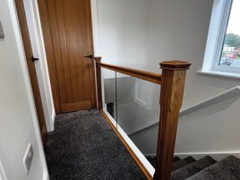 Eine Holztür mit Glasfenster, ein Teppich und eine Treppe sowie ein Fenster mit Blick nach draußen.