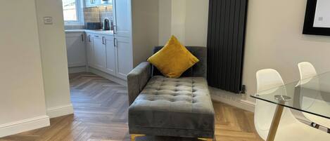 Una sala de estar moderna con un sofá gris, una mesa de vidrio y un cojín amarillo.