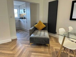 Ein modernes Wohnzimmer mit einem grauen Sofa, einem Glastisch und einem gelben Kissen.