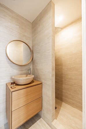 Ein Badezimmer mit einem Holzbadschränken, einem runden Spiegel und einem Aufsatzwaschbecken.