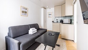 A compact living space with a sofa, a small table, a kitchenette, and a television. - 2 People #1 Bedroom #Invalides #Eiffel Tower #Paris 07 (Paris)
