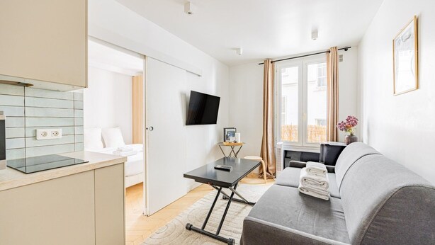 A modern hotel room with a kitchenette, a flat-screen TV, a sofa, and a dining area. - 2 People #1 Bedroom #Invalides #Eiffel Tower #Paris 07 (Paris)