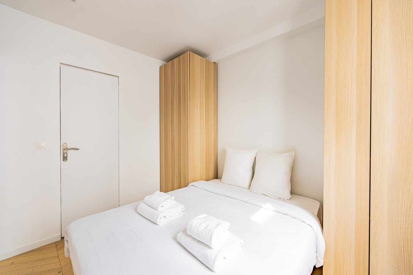 A hotel room with a bed, a wardrobe, and a door.