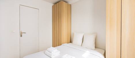A hotel room with a bed, a wardrobe, and a door.