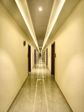 A long, well-lit hallway with doors on both sides, leading to a bright ceiling light.
