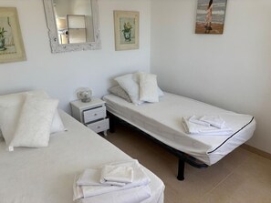 Een slaapkamer met twee eenpersoonsbedden, een nachtkastje en een spiegel.