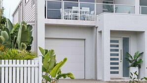 Een modern huis met twee verdiepingen, een balkon, een garage en een verzorgde tuin.