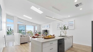 Een moderne keuken met een centraal eiland, witte kastjes en een zwarte vaatwasser.