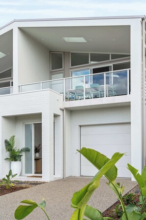 Ein modernes, zweistöckiges Haus mit Balkon, Garage und einem gepflegten Garten.