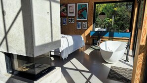 A modern bathroom with a freestanding bathtub, a large window, and artwork on the wall. - Creative summer house 200 metres from beach (Sjællands Odde)