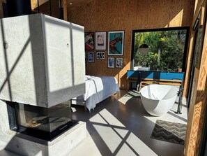 Ein modernes Badezimmer mit einer freistehenden Badewanne, einem großen Fenster und Kunstwerken an der Wand.