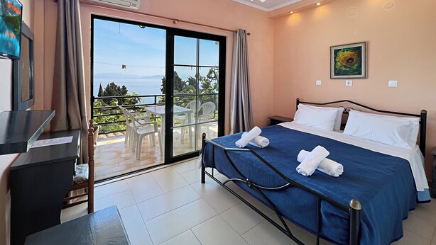 A bedroom with a bed, a desk, and a view of the outdoors. - Charming apartment in quaint Gastouri perfect for relaxing getaway (Gastouri)
