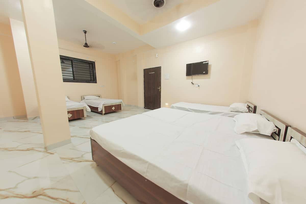 A hotel room with a large bed, a smaller bed, a desk, a chair, a window with blinds, a door, and a mounted television.