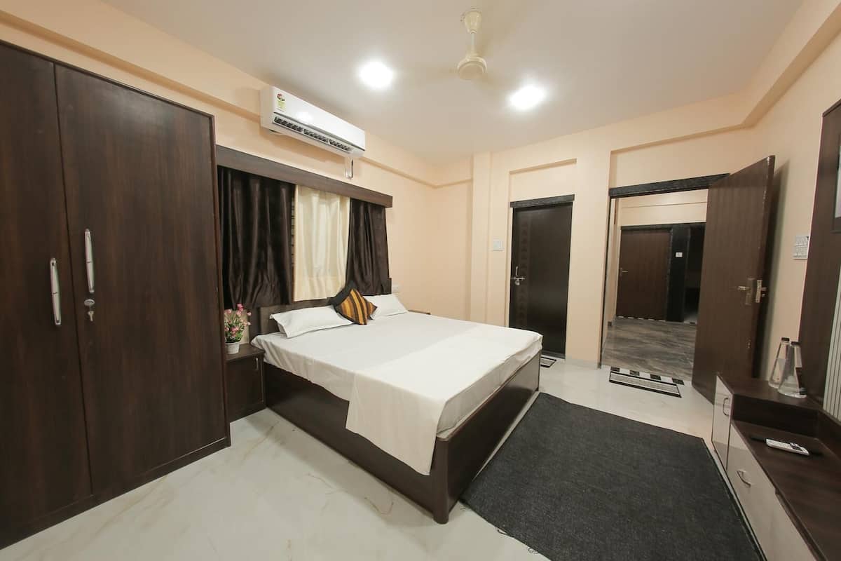 A hotel room with a bed, wardrobe, air conditioning unit, and a ceiling fan.