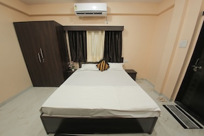 Une chambre Ă coucher comprenant un lit, une armoire, un appareil de climatisation, une table de chevet et une porte.