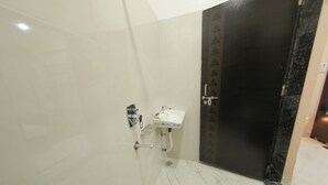A bathroom with a white sink, a mirror, and a shower area. - Tulsi Leela - Home Stay (Dr. Ambedkar Nagar)