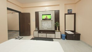 A bedroom with a bed, a TV, a mirror, a cabinet, and a plant. - Tulsi Leela - Home Stay (Dr. Ambedkar Nagar)