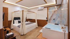 Una camera da letto con un letto, una vasca da bagno vetrata, una testiera in legno e un soffitto con faretti.