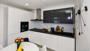 A modern kitchen with white cabinets, a black countertop, and a built-in oven. - Extraordinary Beach house Becir (apartment 1) (Molunat)