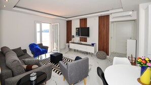 A modern living room with a sofa, a coffee table, a TV, and a dining area with a table and chairs. - Extraordinary Beach house Becir (apartment 1) (Molunat)