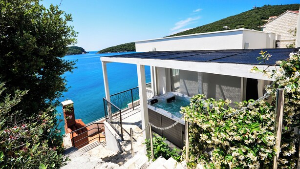 A modern building with a rooftop pool, a staircase leading to a deck, and a view of the sea. - Extraordinary Beach house Becir (apartment 1) (Molunat)