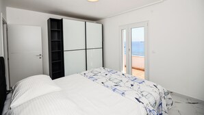 A bedroom with a bed, a wardrobe, a door leading to a balcony with a view of the sea. - Extraordinary Beach house Becir (apartment 1) (Molunat)