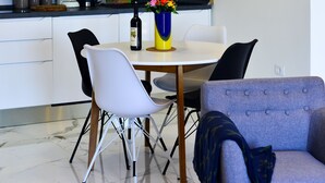 A modern kitchen with dark cabinets, a white dining table, and a blue armchair. - Extraordinary Beach house Becir (apartment 1) (Molunat)