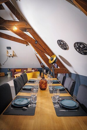 An attic dining room with a long table set for six, wooden beams, and a chandelier. - British Style, projector, foosball & right in the heart of downtown (Le Mans)
