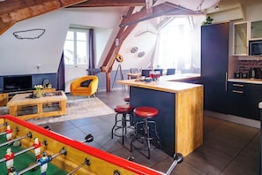 Un espai habitable d'estil loft amb cuina, zona de dinar i taula de futbolí.