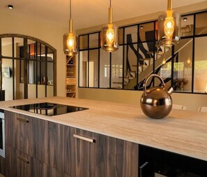 A modern kitchen with a central island, pendant lighting, and a stainless steel kettle. - Exceptional air-conditioned villa with heated pool - Coteaux bordelais (Bouliac)