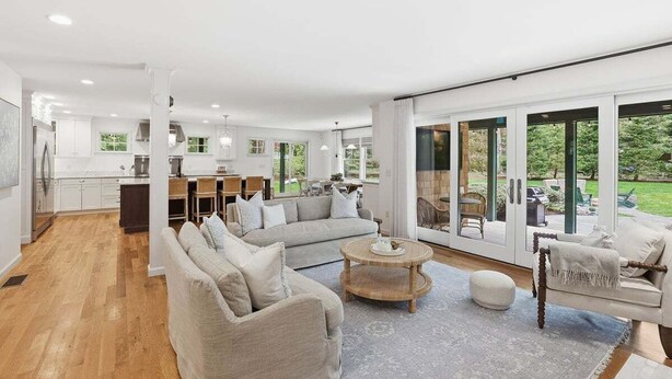 A spacious living area with a sofa, coffee table, and a view of the garden through large sliding doors.