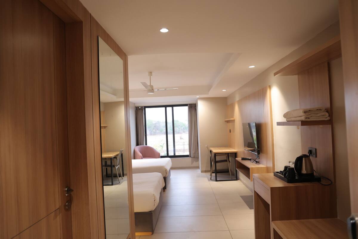 A hotel room with a bed, desk, chair, television, and a view of the outdoors.