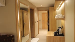 Une chambre d’hôtel avec des portes en bois, un miroir, un porte-serviettes, une machine à café et un petit tapis.