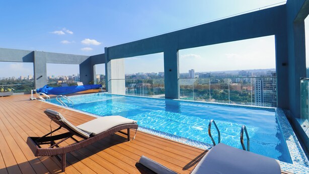 A rooftop infinity pool with lounge chairs, a view of the cityscape, and a clear sky. - Luxury 1 Bedroom in Westlands Nairobi with Pool, Gym & Skyline Views (Nairobi)