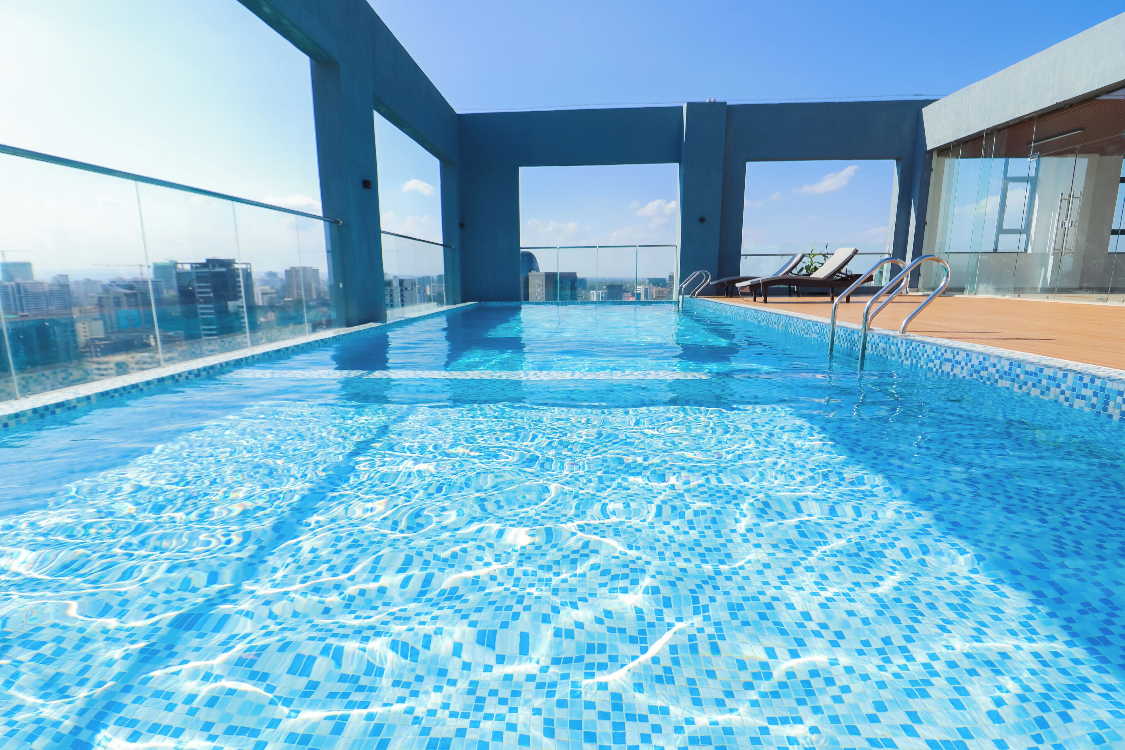 Una piscina a sfioro sul tetto con acqua cristallina, ringhiere in vetro e vista sulla città.
