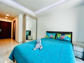 A hotel room with a bed, a mirror, a door, and a small table. - Lagoona Beach Resort 2 Pattaya (Muang Pattaya)