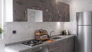 Una cucina moderna con pensili grigi, un frigorifero in acciaio inossidabile e una cucina a gas.