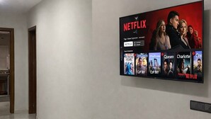 Un corridoio con una grande televisione a schermo piatto montata sulla parete, che mostra l'interfaccia di Netflix con diverse miniature di programmi.
