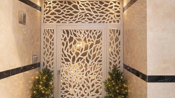 Un corridoio con una porta decorativa, due piante in vaso e due lanterne.
