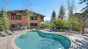 Ett modernt hus med en swimmingpool, utemöbler och utsikt över bergen.