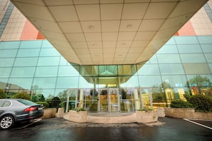 A modern building with a glass facade, a car parked in front, and a gated entrance. - Gateway to Modern Elegance (Bucharest)
