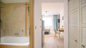 Una habitación de hotel con bañera, cama, escritorio y una silla.