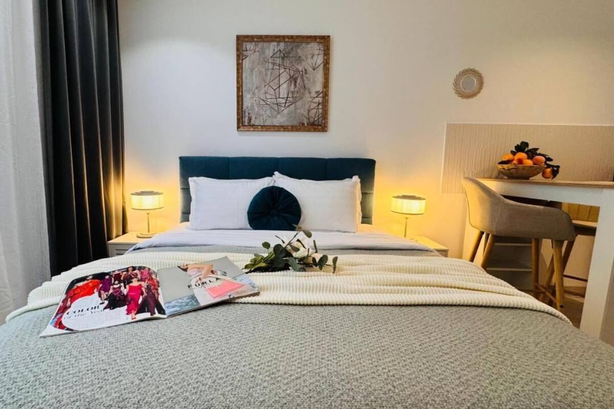 A hotel room with a bed, bedside lamps, a desk, and a chair.